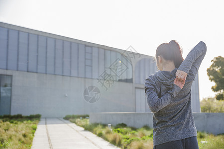 美手阳光素材傍晚运动美女拉伸身体背影背景