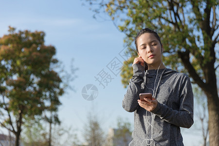 公园运动女孩阳光下休息听音乐高清图片