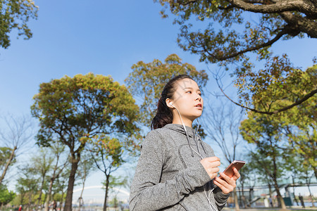 公园运动女孩阳光下休息听音乐高清图片