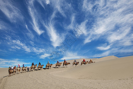 沙漠中骑骆驼前行的人背景图片