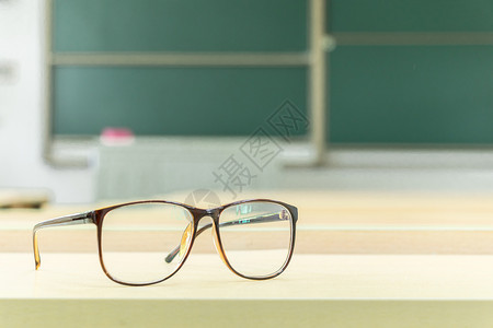 毕业季学校黑板教室里书桌上的眼镜特写背景