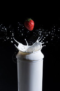 牛奶溅起落入牛奶的草莓背景