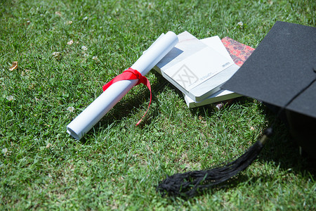 祝毕业书籍大学草地上的书本证书学士帽背景