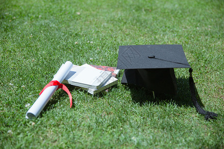 草地书籍素材大学草地上的书本证书学士帽背景