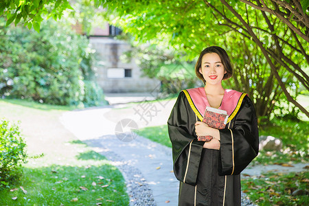 抱书的女人毕业季穿学士服抱书的学生背景