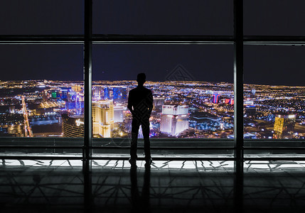 窗户夜景站在办公室俯视城市的男人设计图片