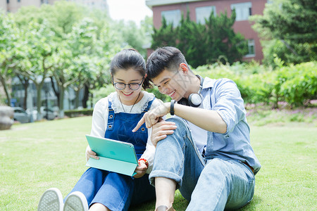 阳光下男女大学生在看平板电脑高清图片