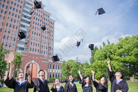 蓝天绿地白云毕业季青春大学生们扔学士帽背景