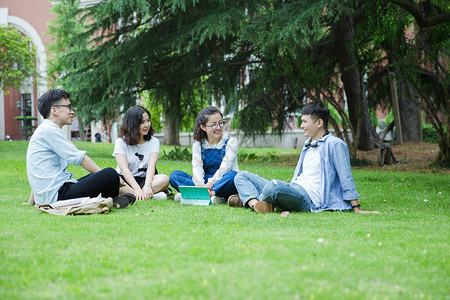 坐男男女大学生们坐草地上聊天休息背景