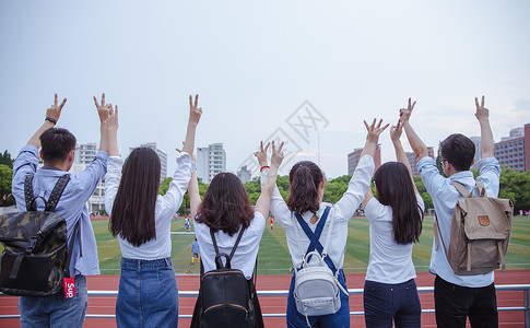 大学毕业生毕业季操场上青春大学们举手比耶背景