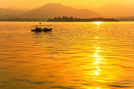 西湖剪影金色夕阳洒满湖面背景