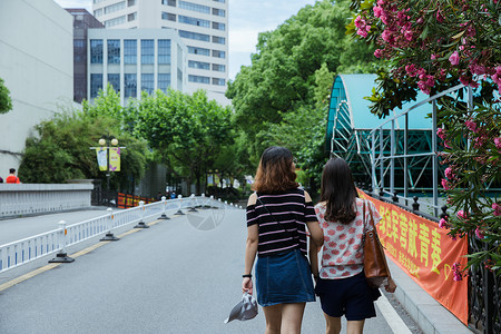 校园路上两个女孩挽手散步背景图片