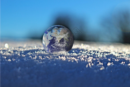 趴在地上的人雪地上的玻璃地球设计图片