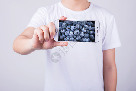 穿短袖的男孩手机中的水果设计图片