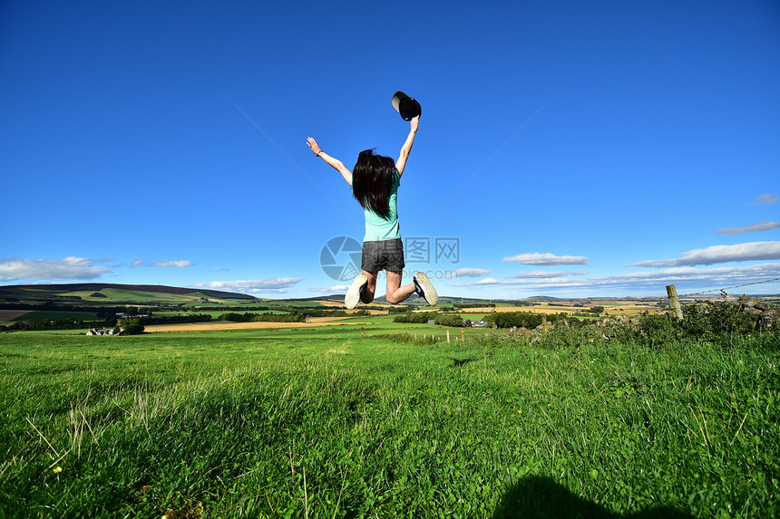 草地上跳跃的女孩图片