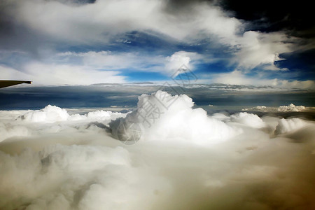 在云端之上飞行在蓝天中的客机机翼背景