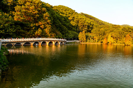 12空桥金黄色夕阳下树林旁湖边上多孔桥倒影在湖里波光粼粼背景