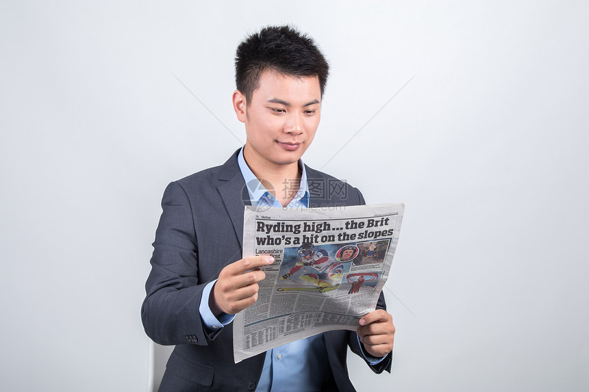 穿着西装坐着看报纸的男人图片
