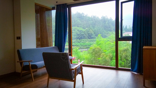 窗外有绿树青山的带落地窗的房间客厅背景图片