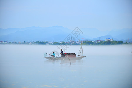 渔夫渔船下涯晨雾背景