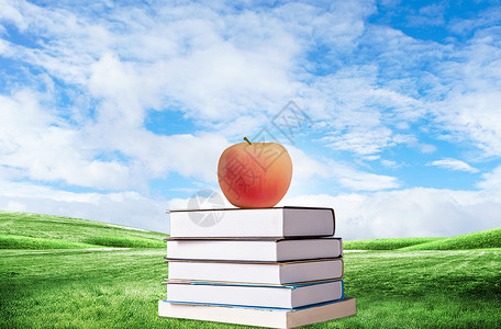 一堆苹果草地上的书设计图片