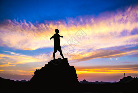 山顶岩石夕阳下站在山顶的人设计图片