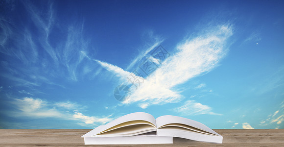 木材桌面蓝天白云下的书设计图片