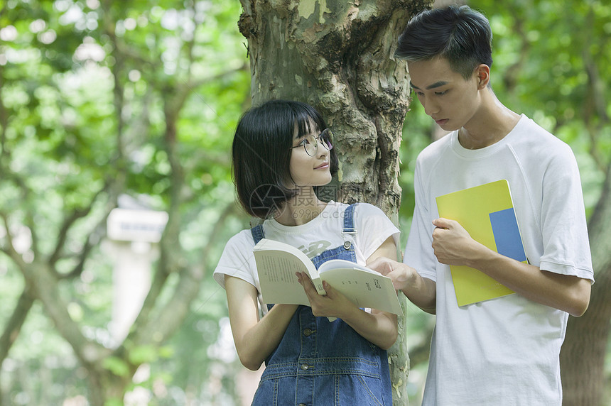 学校林荫道上男女同学下课一起学习看书图片