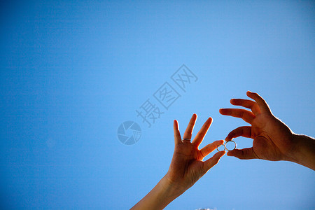 手拿着戒指在蓝天下背景图片