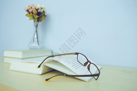 书桌上的书、花瓶和眼镜高清图片