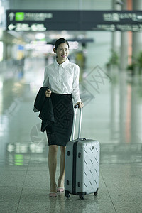 商务女士手提拉杆箱从机场大厅经过背景图片