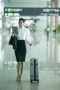 商务女士手提拉杆箱从机场大厅经过并手看ipad背景图片