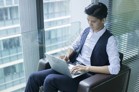 商务楼办公室里商务男士在休闲办公看电脑图片