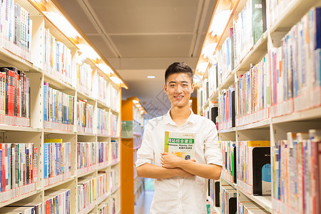 站在图书馆书架旁看书的帅气男同学图片