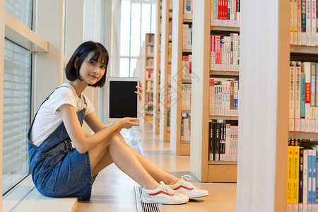 可爱女生鞋坐在图书馆书架旁看书的可爱女生背景
