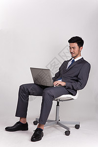 坐着操作笔记本电脑的商务人士背景图片