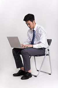 商务男士手拿笔记本电脑操作坐着操作笔记本电脑的商务人士背景
