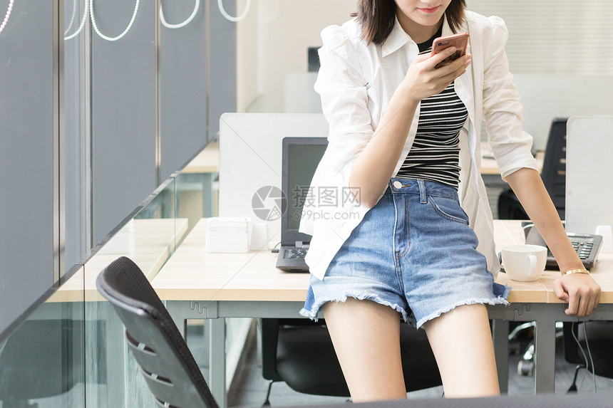 坐着使用手机的办公室女职员图片