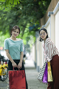 女性闺蜜在小资马路上购物逛街背景图片