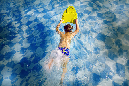 小孩游泳池用浮板游泳的孩子背景