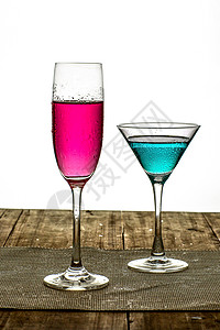 一支装冰的杯子装着粉色与蓝色饮料的杯子放在木桌上背景