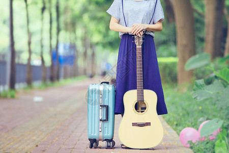 蓝色背带裙小道上的吉他女孩行李箱背景