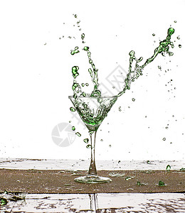 鸡尾酒在室内绿色饮料溅在玻璃杯中的水珠背景