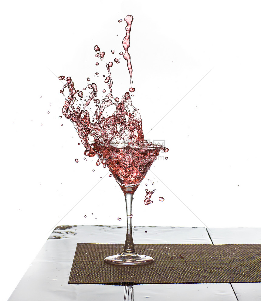 粉红色饮料溅在玻璃杯中的水珠图片