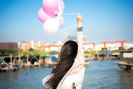 拿着气球的年轻女性背影图片