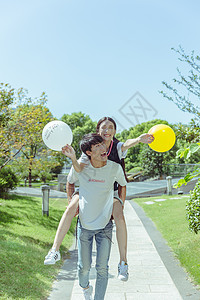 情人节公园情侣背起玩气球背景图片