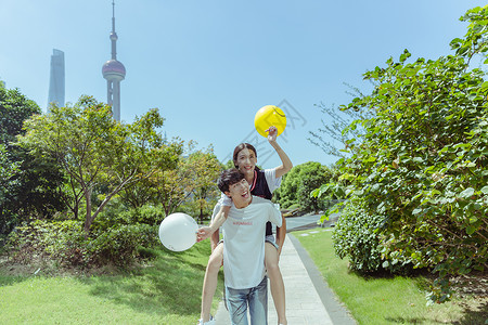 情人节公园情侣背起玩气球背景图片