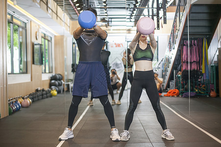 肌肉爆发男性女性在健身房一起健身背景