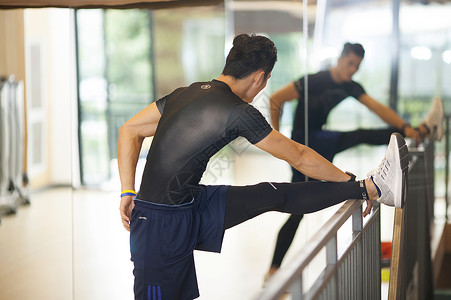 男性在健身房里练习压腿做热身运动图片