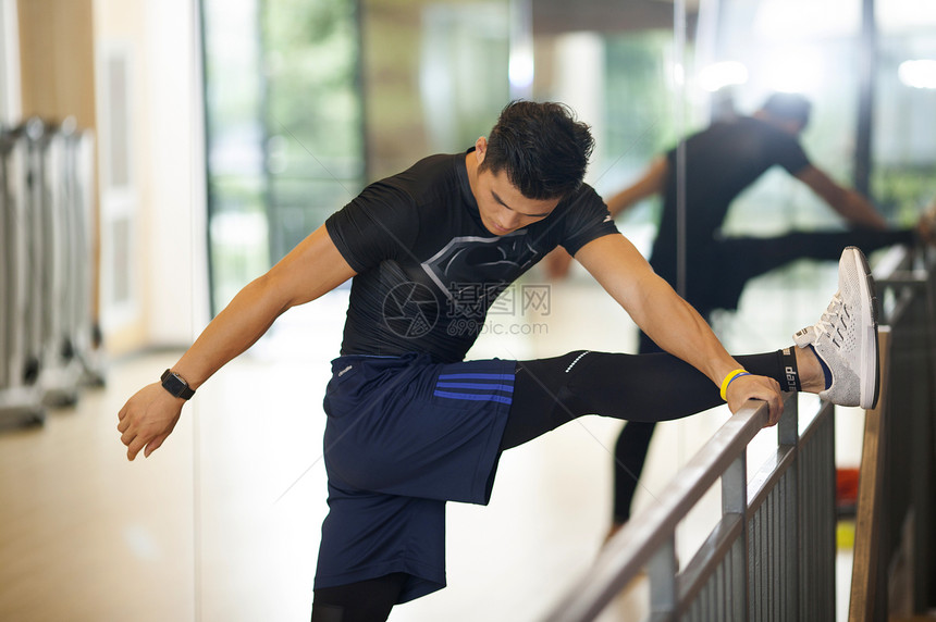 男性在健身房里练习压腿做热身运动图片